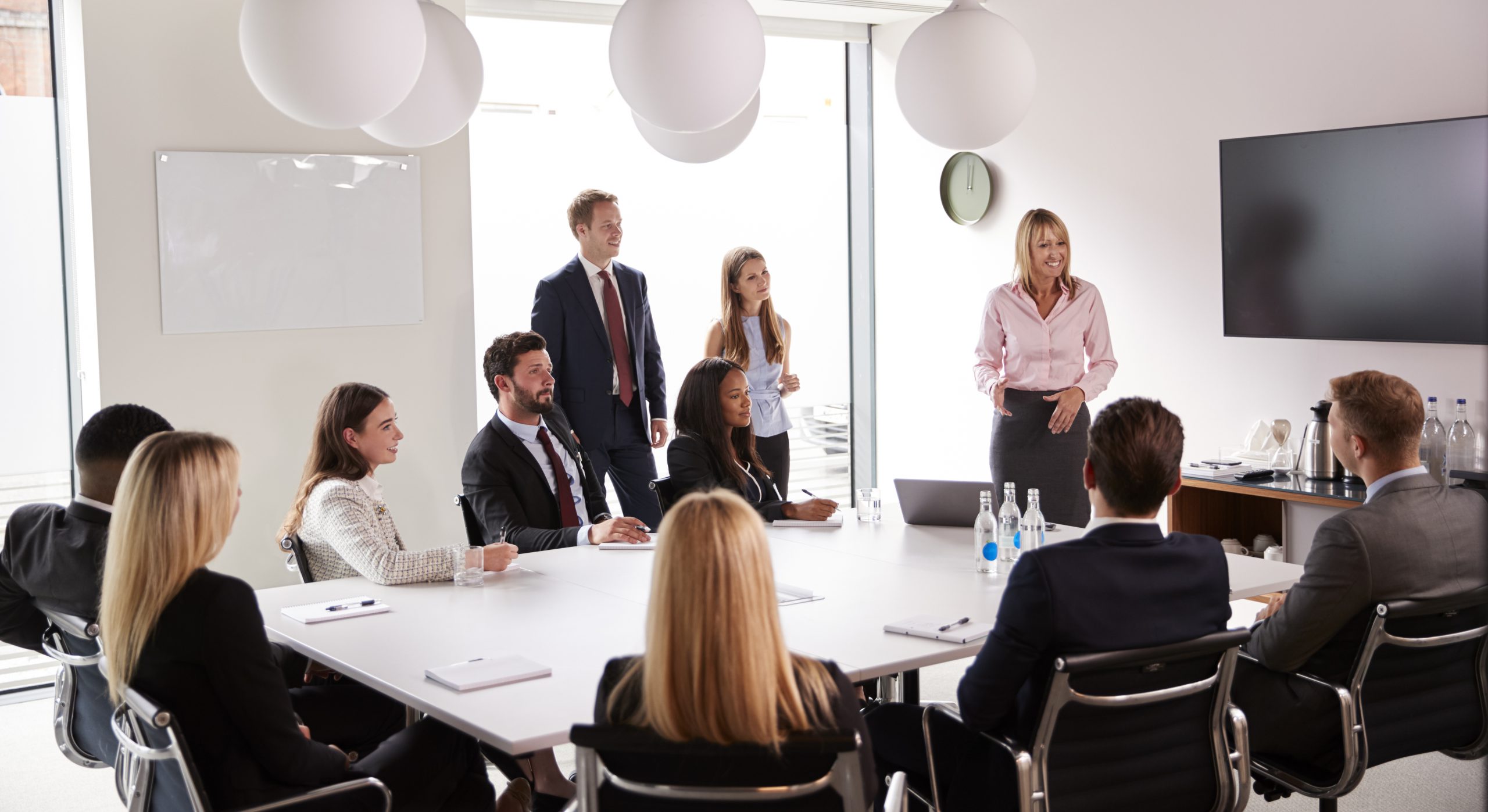 Mature Businesswoman Addressing Group Meeting Around Table At Graduate Recruitment Assessment Day